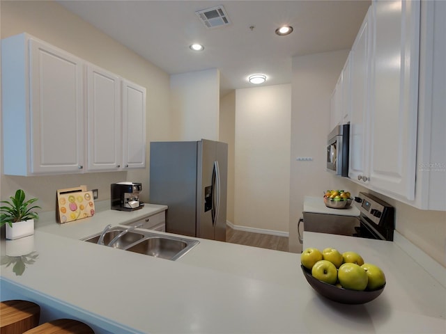 kitchen with stainless steel appliances, a sink, visible vents, white cabinetry, and light countertops