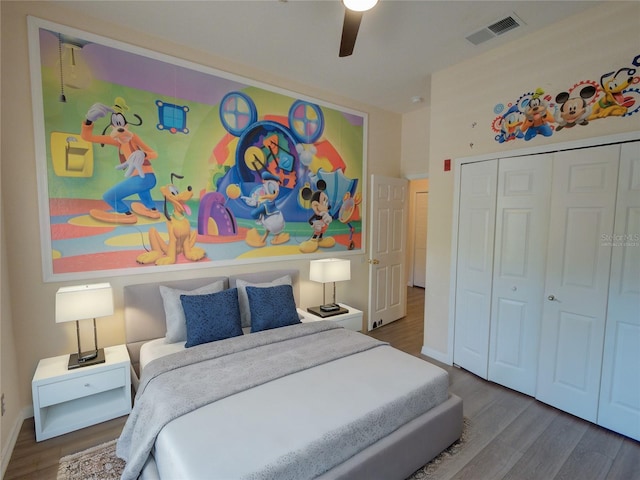 bedroom featuring wood finished floors, visible vents, baseboards, a ceiling fan, and a closet