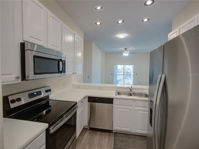 kitchen with stainless steel appliances, recessed lighting, light countertops, white cabinets, and a sink