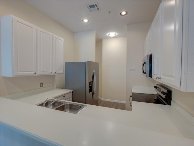 kitchen featuring stainless steel appliances, white cabinets, visible vents, and a sink