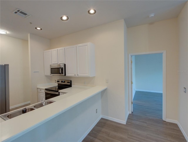 kitchen with visible vents, appliances with stainless steel finishes, white cabinets, wood finished floors, and baseboards