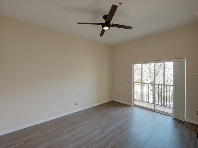 spare room featuring wood finished floors, a ceiling fan, and baseboards