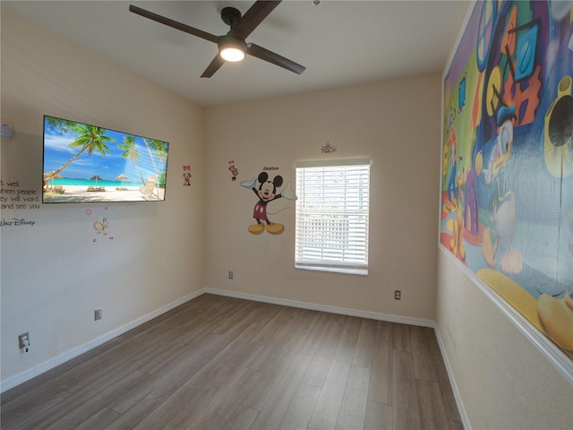 empty room with wood finished floors, a ceiling fan, and baseboards