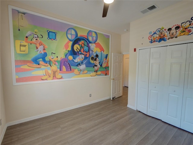 unfurnished bedroom featuring ceiling fan, wood finished floors, visible vents, baseboards, and a closet