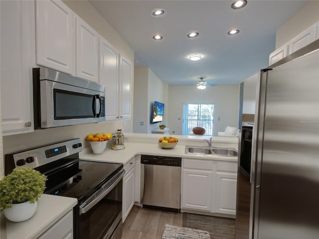 kitchen with stainless steel appliances, recessed lighting, light countertops, white cabinets, and a sink