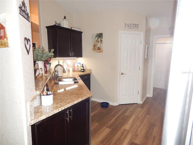 bar with dark wood-style floors, a sink, and baseboards