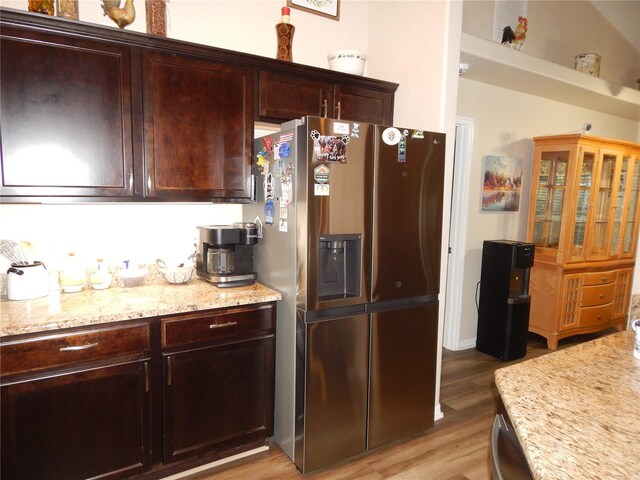 kitchen featuring light stone counters, light wood-type flooring, dark brown cabinetry, and stainless steel refrigerator with ice dispenser