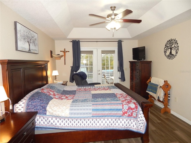 bedroom featuring access to exterior, a tray ceiling, french doors, wood finished floors, and baseboards