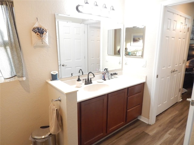 bathroom featuring double vanity, a textured wall, a sink, and wood finished floors