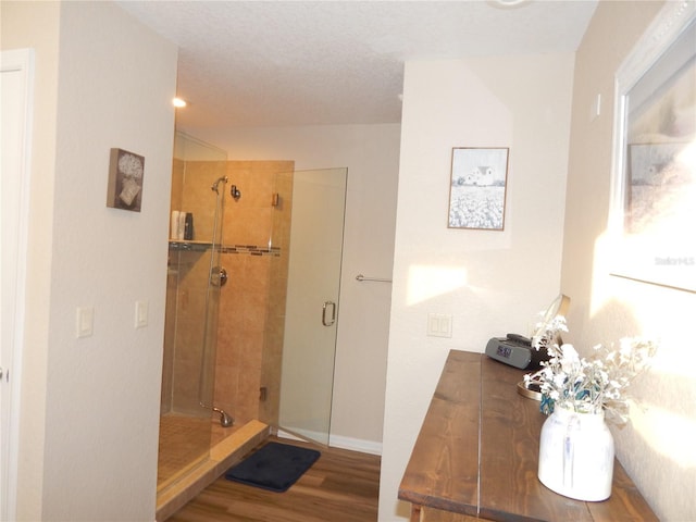 full bath featuring a stall shower, baseboards, and wood finished floors