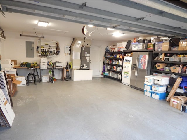 garage featuring heating unit, electric panel, and stainless steel fridge with ice dispenser