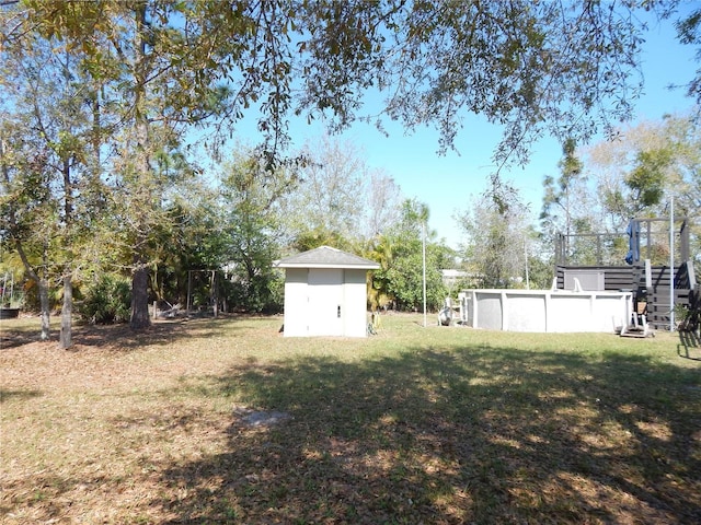 view of yard featuring an outdoor pool, an outdoor structure, and a storage unit