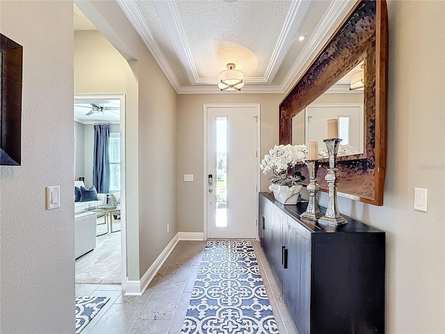 foyer entrance featuring a textured ceiling, ornamental molding, and baseboards