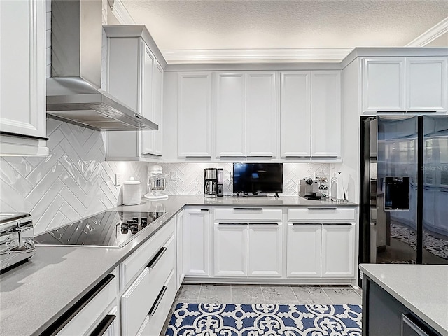 kitchen with decorative backsplash, wall chimney exhaust hood, fridge with ice dispenser, black electric cooktop, and a textured ceiling