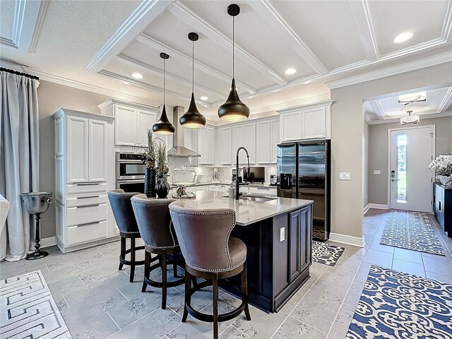 kitchen featuring a center island with sink, crown molding, decorative backsplash, white cabinetry, and refrigerator with ice dispenser