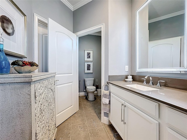 bathroom with crown molding, stone tile floors, toilet, vanity, and baseboards