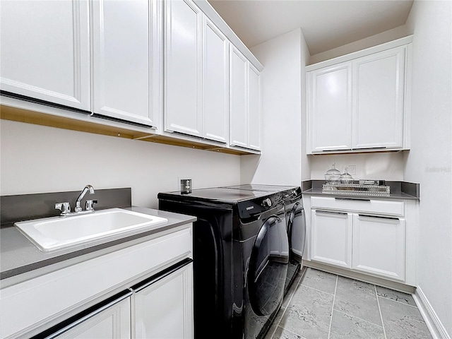 washroom with cabinet space, baseboards, a sink, and independent washer and dryer