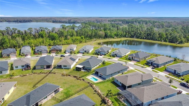 drone / aerial view with a water view, a wooded view, and a residential view