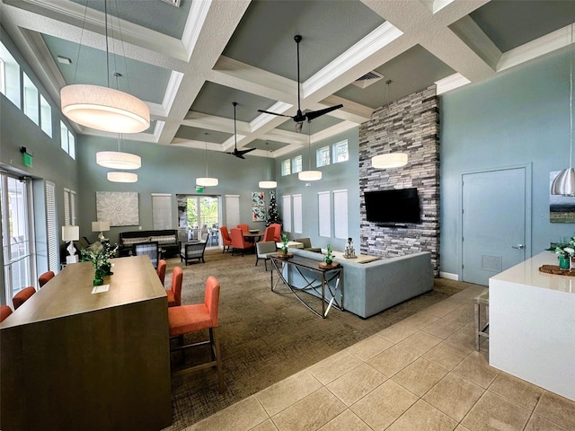 tiled living room featuring beam ceiling, coffered ceiling, ceiling fan, and a towering ceiling