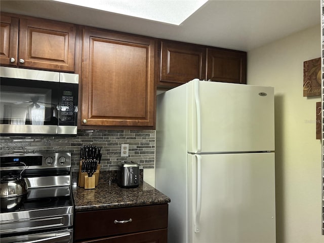 2494 Sweetwater Club Cir Unit 55, Kissimmee, FL 34746 - kitchen with appliances with stainless steel finishes, decorative backsplash, and dark stone countertops