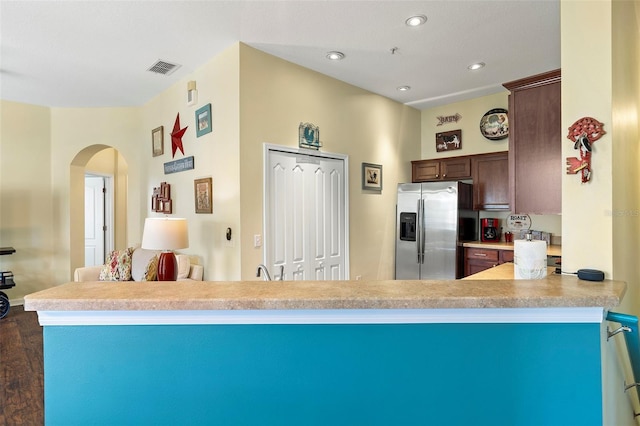 kitchen featuring visible vents, arched walkways, a peninsula, light countertops, and stainless steel refrigerator with ice dispenser