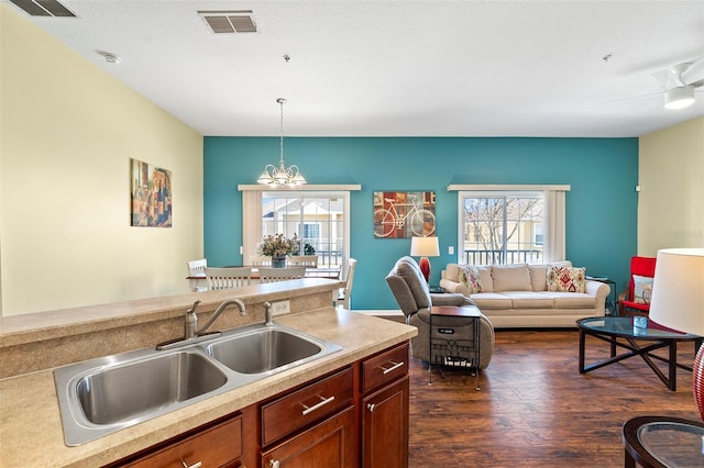 kitchen with dark wood-style flooring, a notable chandelier, light countertops, visible vents, and a sink