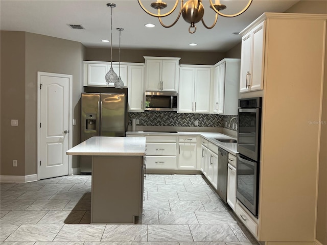 kitchen with a sink, visible vents, a center island, appliances with stainless steel finishes, and decorative backsplash