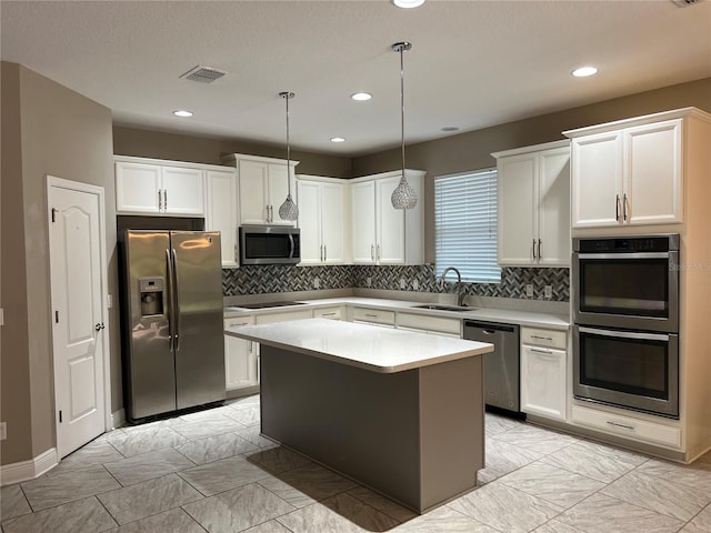 kitchen with visible vents, appliances with stainless steel finishes, light countertops, white cabinetry, and a sink