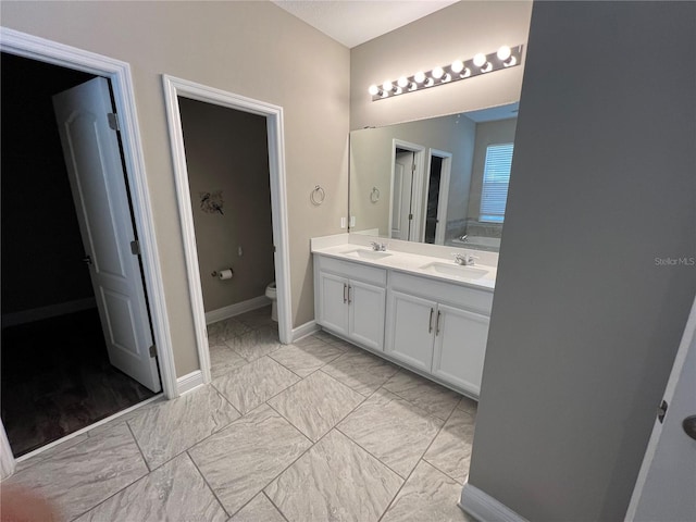 bathroom with marble finish floor, a sink, toilet, and double vanity