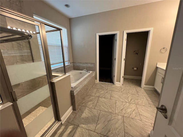 full bathroom featuring vanity, a shower stall, a bath, and baseboards