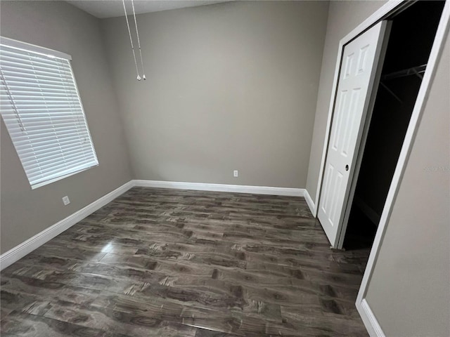 interior space with a closet, baseboards, and dark wood-style flooring