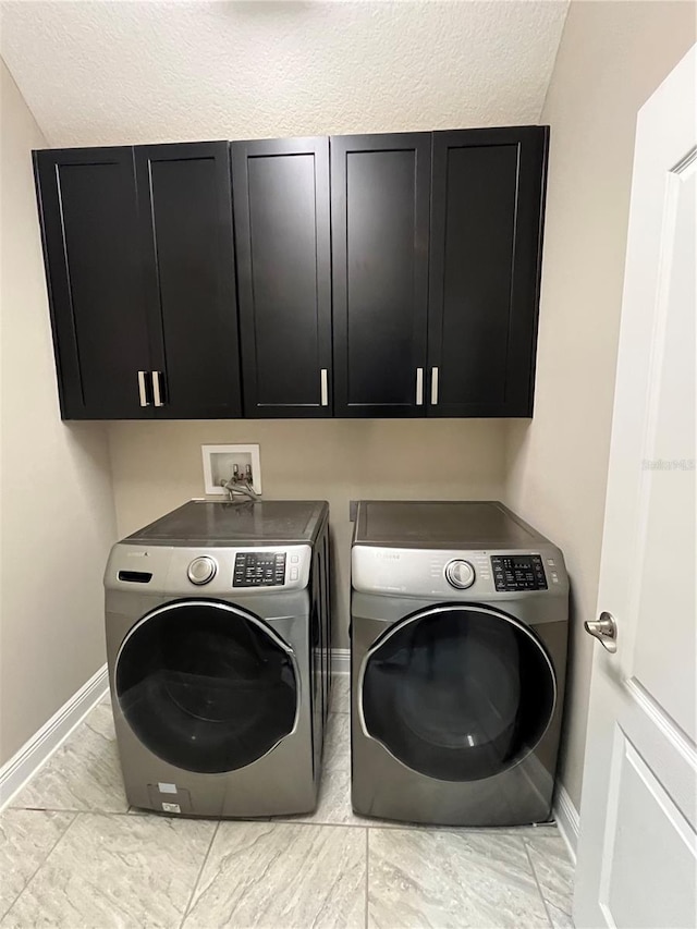 laundry area featuring baseboards, cabinet space, marble finish floor, and washing machine and clothes dryer