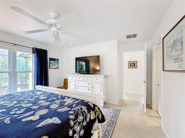 bedroom featuring visible vents, light tile patterned flooring, ceiling fan, a textured ceiling, and baseboards