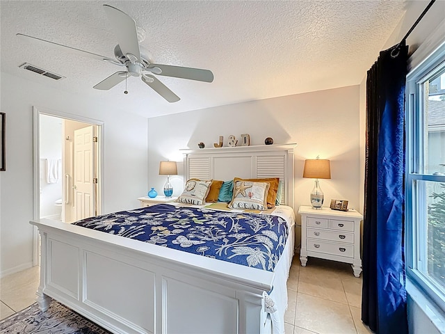 bedroom featuring light tile patterned floors, a textured ceiling, ensuite bathroom, visible vents, and a ceiling fan