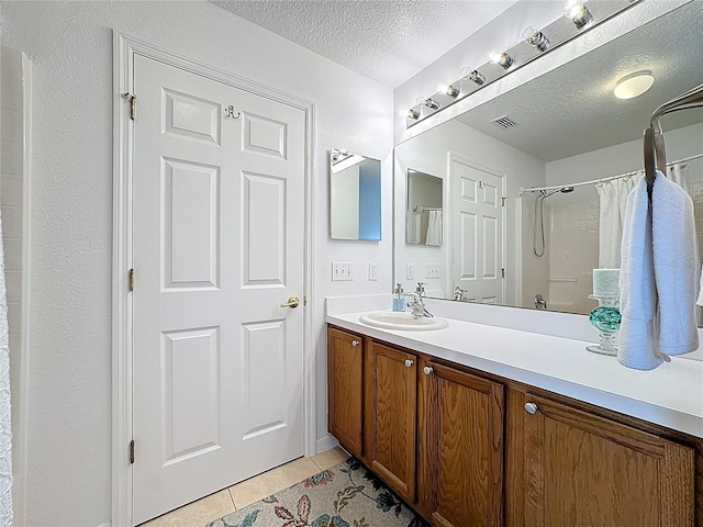 full bath featuring a textured ceiling, vanity, visible vents, and tile patterned floors