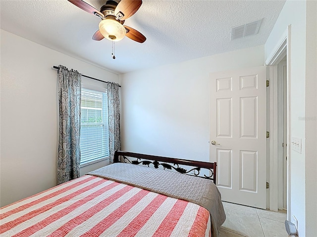 bedroom with visible vents, ceiling fan, a textured ceiling, and light tile patterned flooring