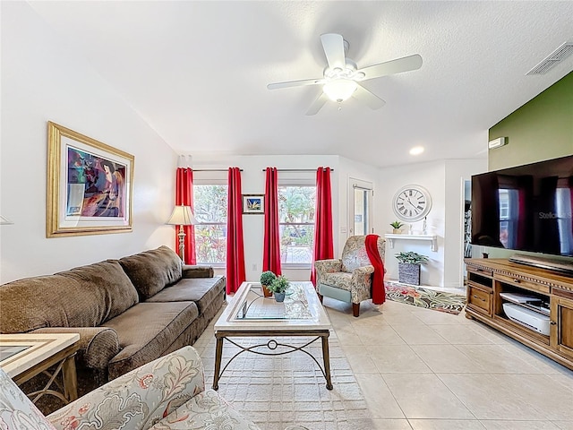 living area featuring light tile patterned floors, lofted ceiling, visible vents, ceiling fan, and a textured ceiling