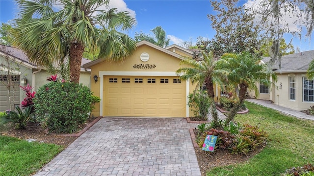 ranch-style house with a garage, a front lawn, decorative driveway, and stucco siding