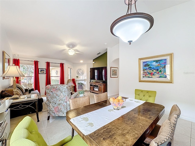 tiled dining area featuring a ceiling fan, lofted ceiling, visible vents, and baseboards