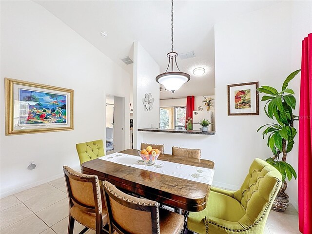 dining space with lofted ceiling, light tile patterned floors, visible vents, and baseboards