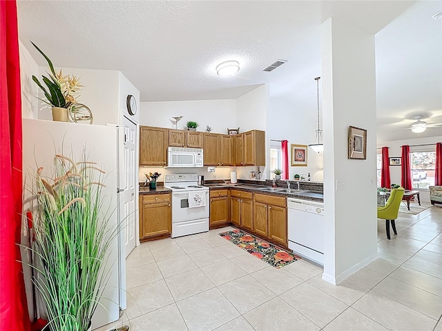 kitchen featuring dark countertops, visible vents, brown cabinetry, a textured ceiling, and white appliances