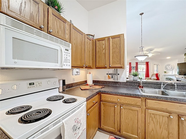 kitchen featuring dark countertops, white appliances, brown cabinetry, and a sink