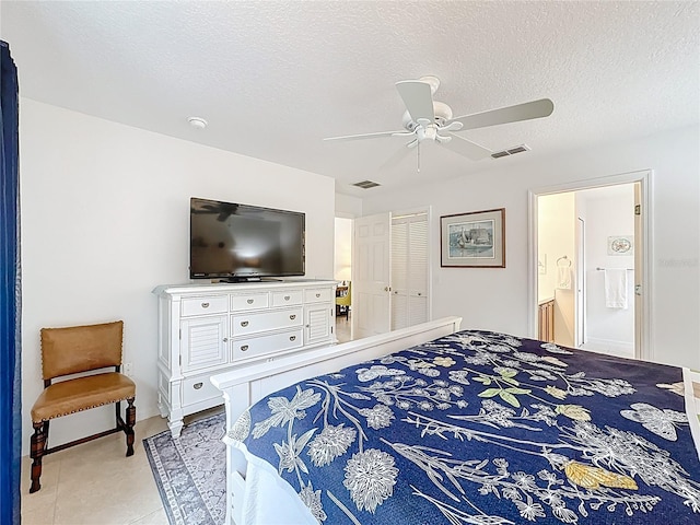 bedroom with a textured ceiling, connected bathroom, visible vents, and a ceiling fan