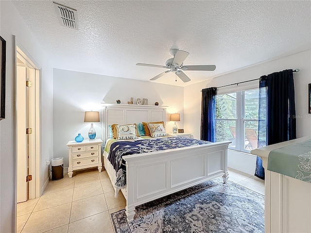 bedroom featuring light tile patterned floors, ceiling fan, a textured ceiling, and visible vents