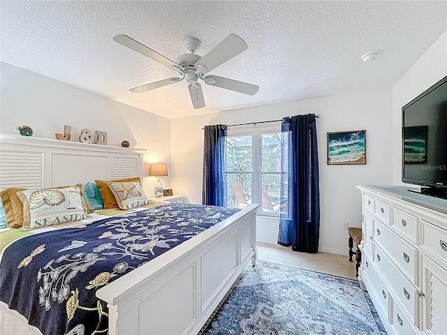 bedroom with a ceiling fan, light tile patterned flooring, and a textured ceiling