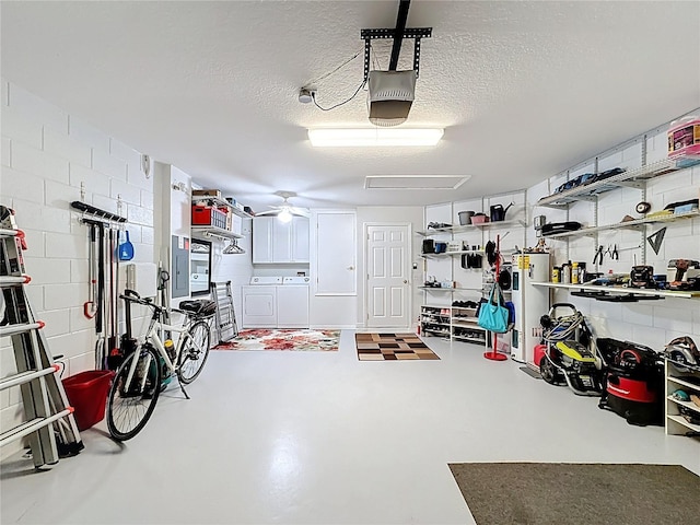 garage with concrete block wall, a garage door opener, water heater, ceiling fan, and washer and dryer