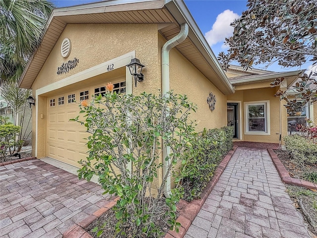 entrance to property with stucco siding and decorative driveway