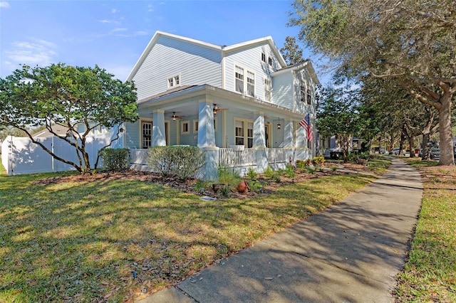 view of side of home with covered porch, a yard, fence, and a ceiling fan