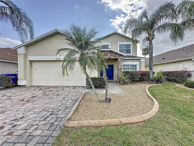 view of front of house with a garage, a front yard, decorative driveway, and stucco siding