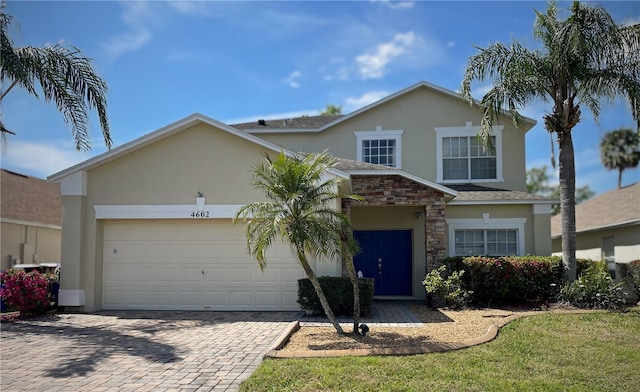 traditional-style house featuring decorative driveway, a garage, stone siding, and stucco siding